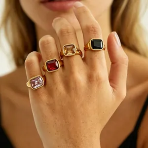 Detail showing four elegant titanium steel rings with colorful square gemstones on a hand.