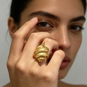 Primo piano di un anello in acciaio inossidabile dorato a forma di conchiglia al dito.