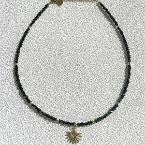 Collar artesanal con colgante de sol, piedras naturales negras y detalles dorados