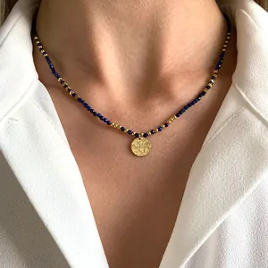 Detalle de un collar vintage de piedra natural con cuentas azules y colgante de sol dorado.
