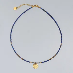 Collar de cuentas finas con piedras naturales azules y colgante de moneda de oro martillado.