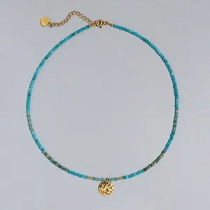 Detalle del collar de piedra natural turquesa con colgante de sol en oro martillado.