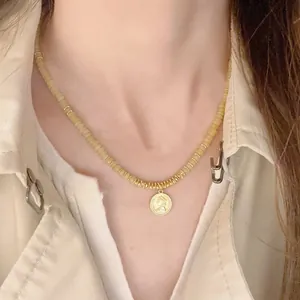 Detalle de un collar vintage de piedras naturales con un colgante de moneda de oro.