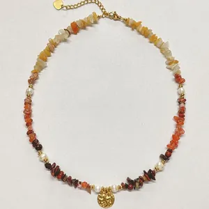Detalle de collar de piedras naturales con un colgante de sol en oro martillato a mano.