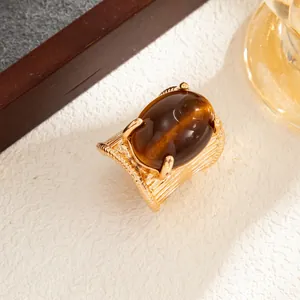 Close-up detail of a vintage gold-toned wide band ring with a large oval amber gemstone