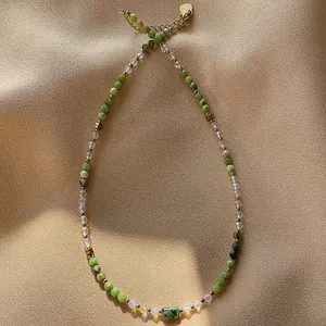 Detailed macro view of handmade beaded necklace with green faceted natural stones.