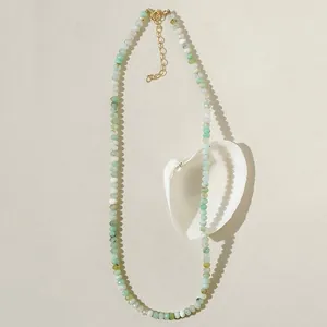 Handmade faceted natural stone beaded necklace with gold spacers on cream background
