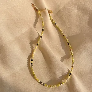 Close-up of faceted natural stone beaded necklace with gold chain on silk fabric