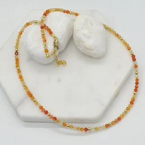 Detail view of handmade faceted orange natural stone necklace with gold-toned spacers