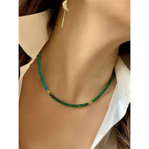 Close-up of a handmade natural stone beaded necklace with gold spacers on a model's neck.