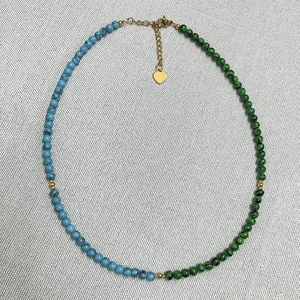 Detail of handmade beaded necklace with green and blue natural stones and gold beads