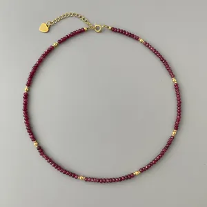 Close-up of faceted dark red natural stone necklace with gold spacer beads and heart charm