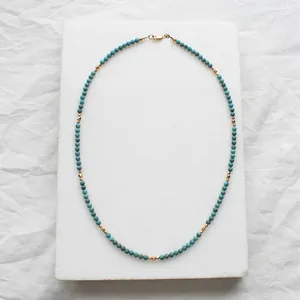 Detailed view of turquoise beaded necklace featuring faceted gold spacer beads on stone