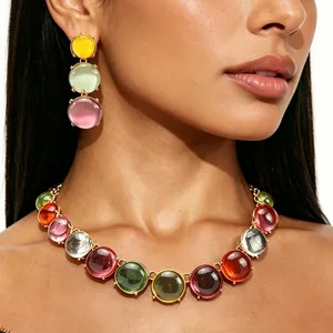 Close-up of geometric colorful resin necklace and matching triple drop earrings on model.