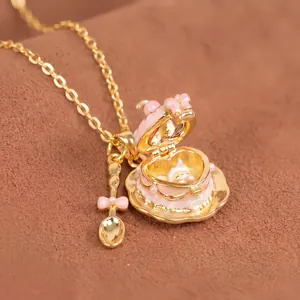 Primer plano detallado del collar relicario de taza de esmalte rosa con cuchara de oro