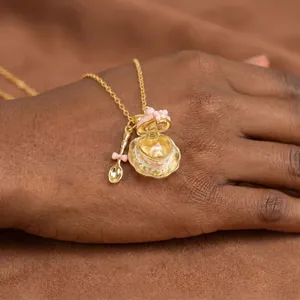 Detalle de collar relicario en forma de taza con dije de cuchara bañado en oro de 18k