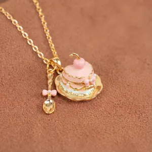 Vista macro que muestra detalles del collar de pastel de corazón rosa y mini cuchara de oro.