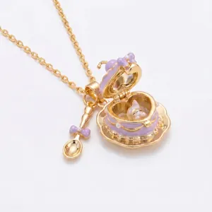 Detalle del collar con relicario chapado en oro de 18k, taza de té lila y cuchara