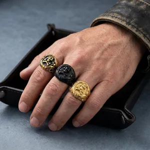 Vista dettagliata di anelli teschio vintage in acciaio al titanio oro e nero sulla mano.