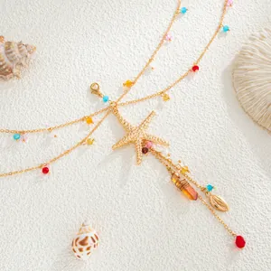 Close-up of bohemian starfish shell body chain with colorful beads on white sand background