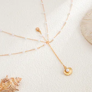 Detail view of a gold seashell pendant body chain with delicate pearls and multi-layer design