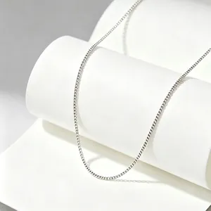 Close-up detail of a minimalist titanium steel necklace chain on an elegant white prop