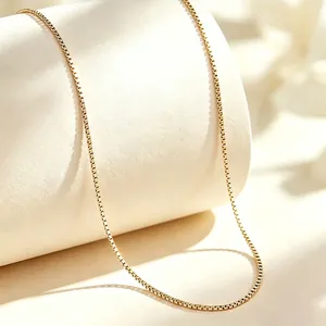Close-up detail of a minimalist gold titanium steel box chain necklace with polished finish