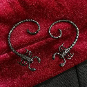 Detailed view of vintage scorpion metal hand bracelets on red velvet backdrop.