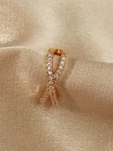 Close-up of a gold-plated ear cuff with a crossed design and inlaid cubic zirconia detail