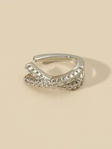 Macro view of a silver-toned cross hollow ear cuff inlaid with sparkling zircons