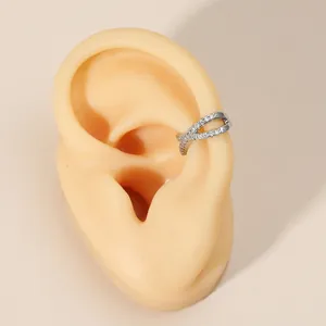 Close-up detail of silver-colored cross hollow ear cuff with sparkling cubic zirconia