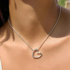 Detailaufnahme einer eleganten Herz-Halskette aus Silber an einer Schlangenkette.