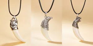 Detailed view of resin wolf tooth pendants with eagle, wolf, and elephant motifs.