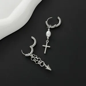 Detail view of asymmetric silver-tone earrings with pearl cross and chain spike charms