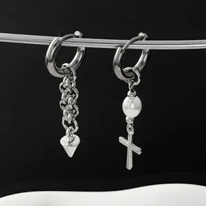 Detail of mismatched silver-toned hoop earrings with pearl, cross, and chain pendants.