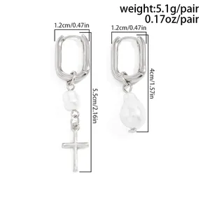 Close-up showing dimensions of asymmetrical silver hoop earrings with pearl and cross
