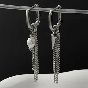 Close-up detail of silver-toned asymmetric tassel earrings with pearl and cone charms