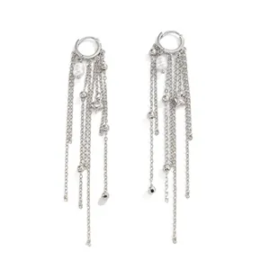 Detailed macro view of silver tassel earrings featuring long chains, white pearls and heart charms