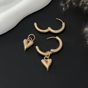 Detailed shot of gold heart hoop earrings with detachable charms on black background