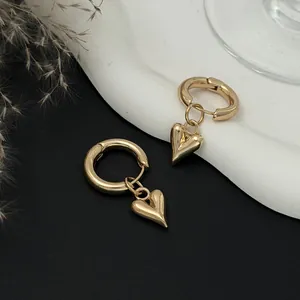 Macro view of elegant gold hoop earrings with polished heart pendants on black background