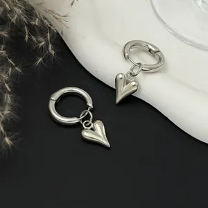 Close-up of vintage silver heart pendant huggie earrings on a minimalist display