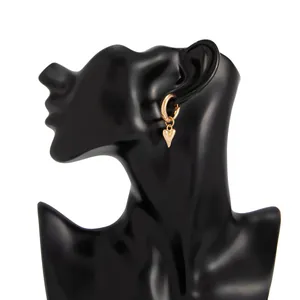 Close-up of a stylish gold hoop earring featuring a minimalist heart pendant on a model