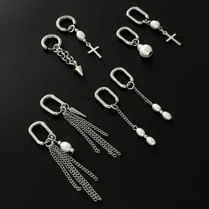 Silver hoop earrings set with pearls, crosses, and chain tassels on a black background