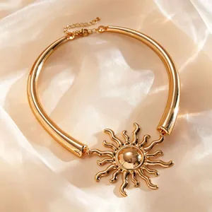 Dettaglio macro di una collana dorata con pendente a sole su elegante tessuto di seta