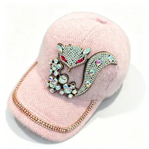 Gros plan sur le bonnet d'hiver en velours rose avec renard en strass et bordure.