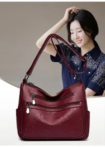 Gros plan d'un sac en cuir bordeaux avec motif trèfle gaufré et détails à fermetures éclair