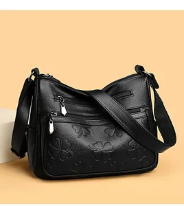 Vue détaillée d'un sac bandoulière noir en cuir avec des motifs trèfles embossés