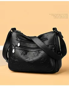 Petit sac bandoulière noir en cuir avec motif floral embossé et multi-fermetures.