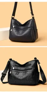 Vue détaillée d'un sac à bandoulière en cuir noir avec motifs trèfles à quatre feuilles.