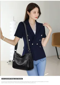 Détail du sac bandoulière en cuir noir avec motifs trèfle à quatre feuilles et zips argentés